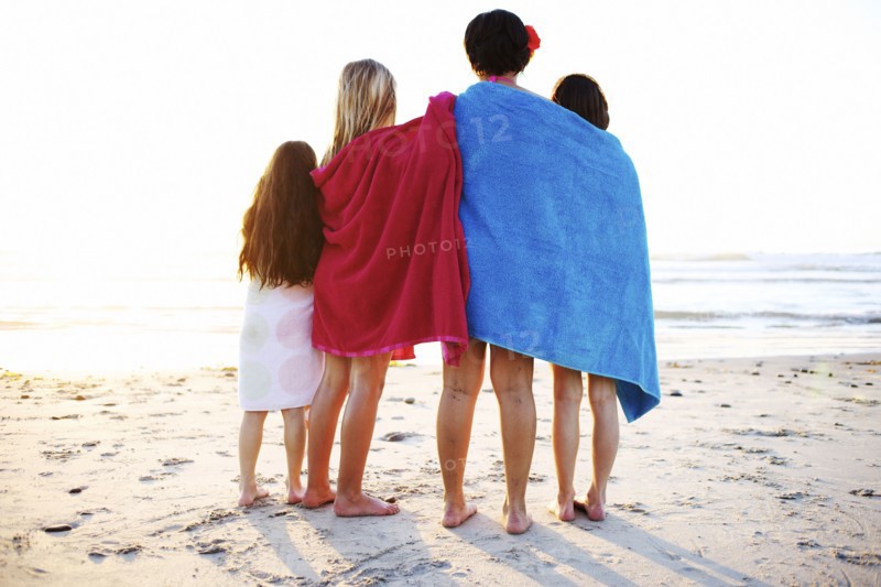 Girls wrapped in towels standing on beach