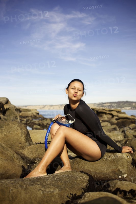 Mixed race woman holding snorkel on rocks