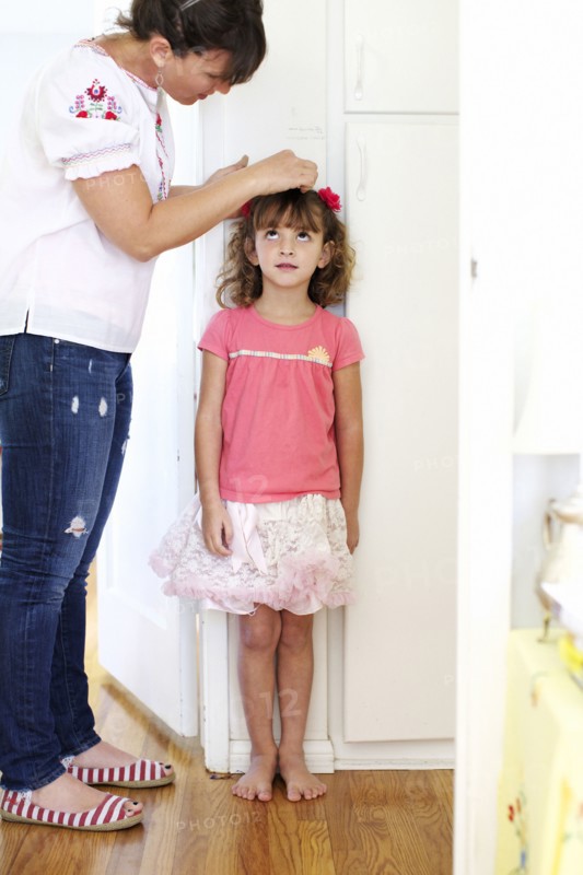 Mother measuring daughter's height