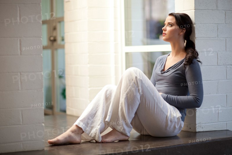 Woman sitting on floor leaning on wall