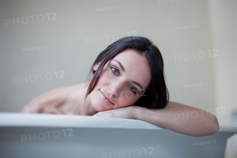 Caucasian woman leaning on side of bathtub
