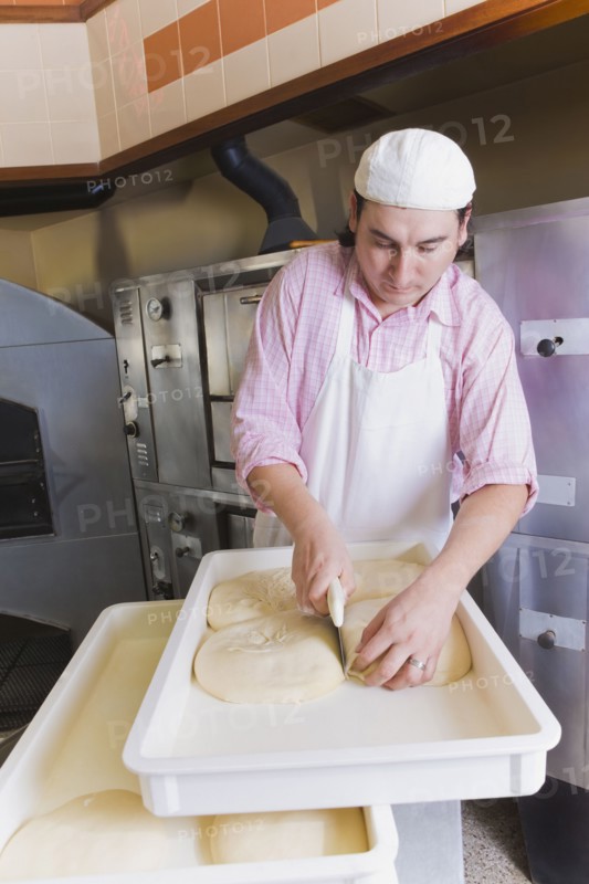 Hispanic man cutting pizza dough