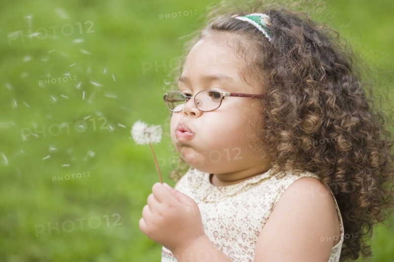 Hispanic girl blowing dandelion
