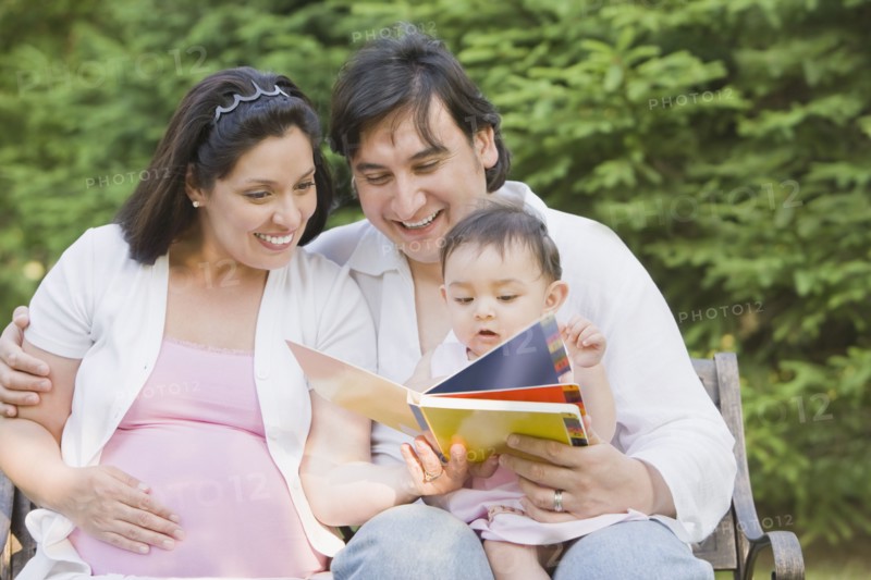 Hispanic mother and father reading to daughter