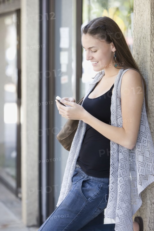Hispanic woman text messaging on cell phone