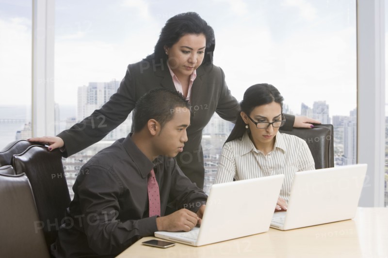Business people in meeting using laptops