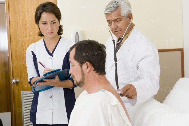 Doctor and nurse examining patient in hospital room