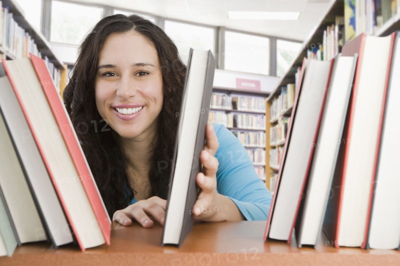 Mixed race woman looking for book in library