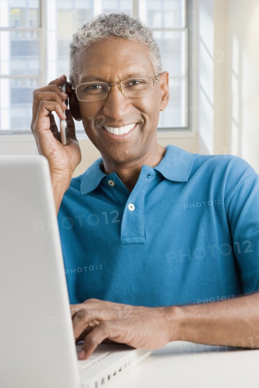 Mixed race man with laptop talking on cell phone