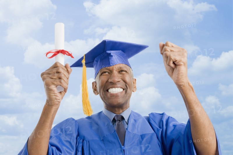 Mixed race man in graduation cap and gown holding diploma