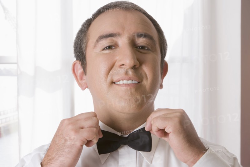 Hispanic man tying bow tie