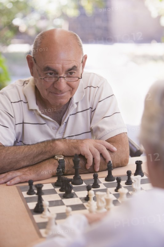 Senior men playing chess outdoors
