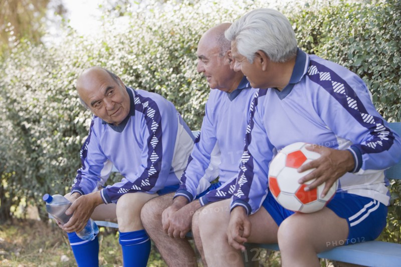 Senior Chilean soccer players sitting on bench