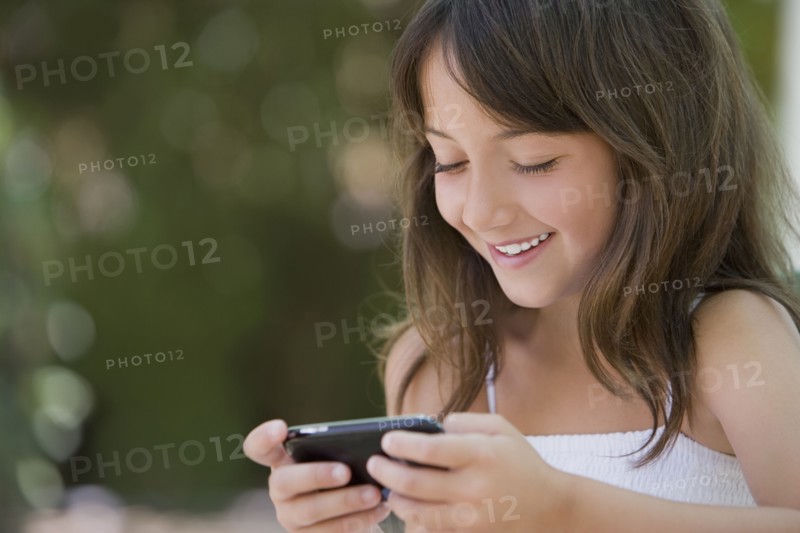 Hispanic girl text messaging on cell phone