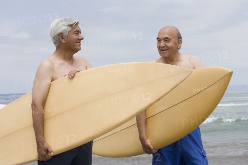 Senior Hispanic men holding surfboards on beach