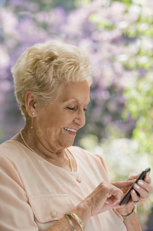Senior Hispanic woman text messaging on cell phone