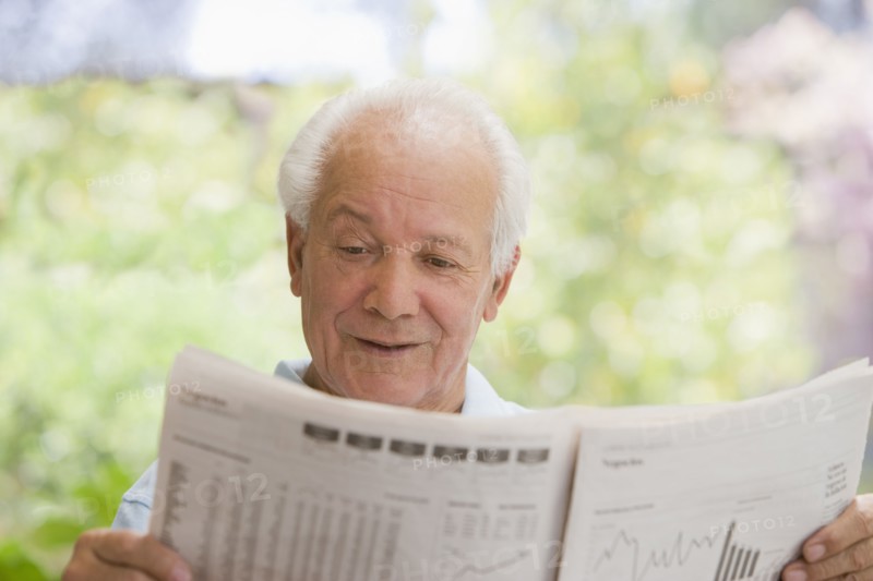 Senior Hispanic man reading financial newspaper