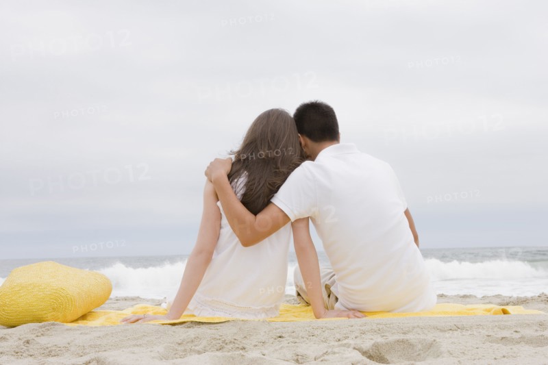 Hispanic couple sitting on beach together