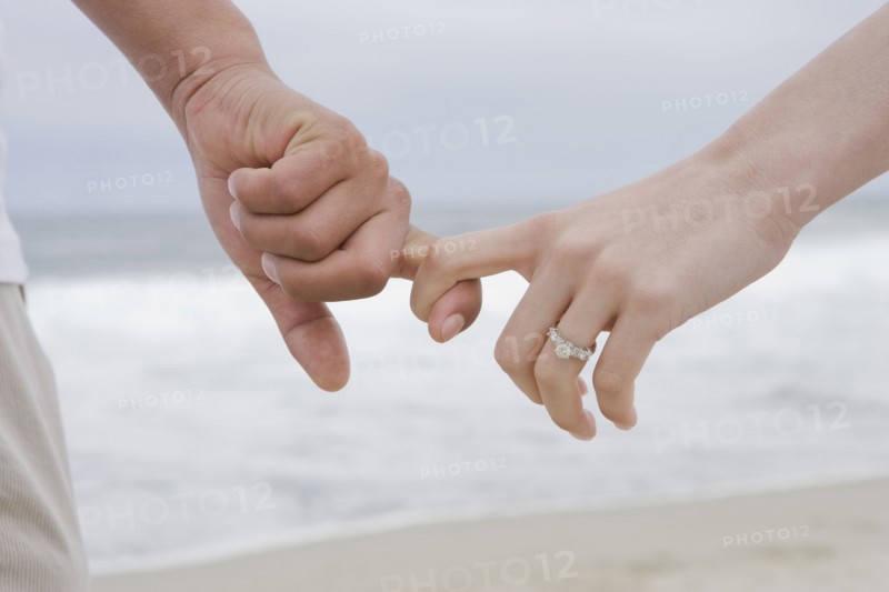 Hispanic couple holding hands on beach