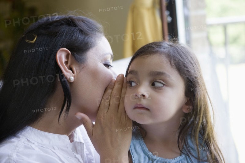 Hispanic mother whispering to daughter