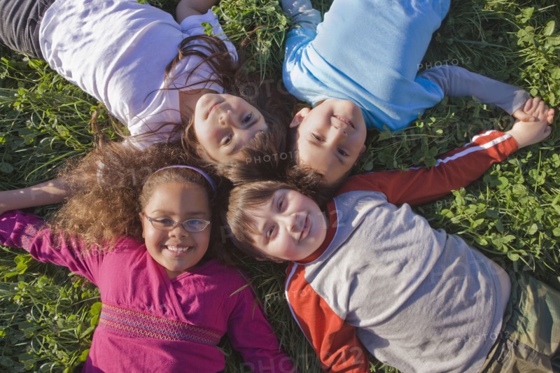 Hispanic children laying in grass together