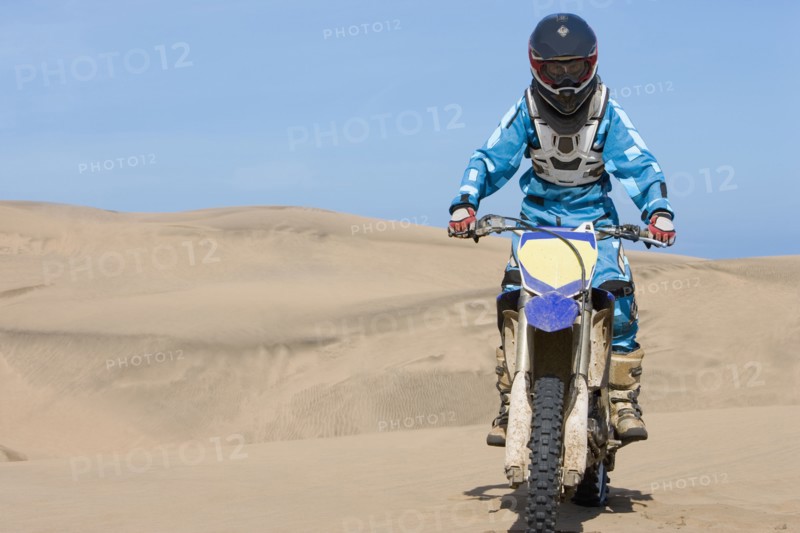 Chilean teenager riding motorcycle on sand dune