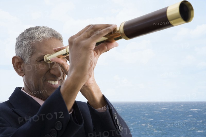 Mixed race businessman using telescope