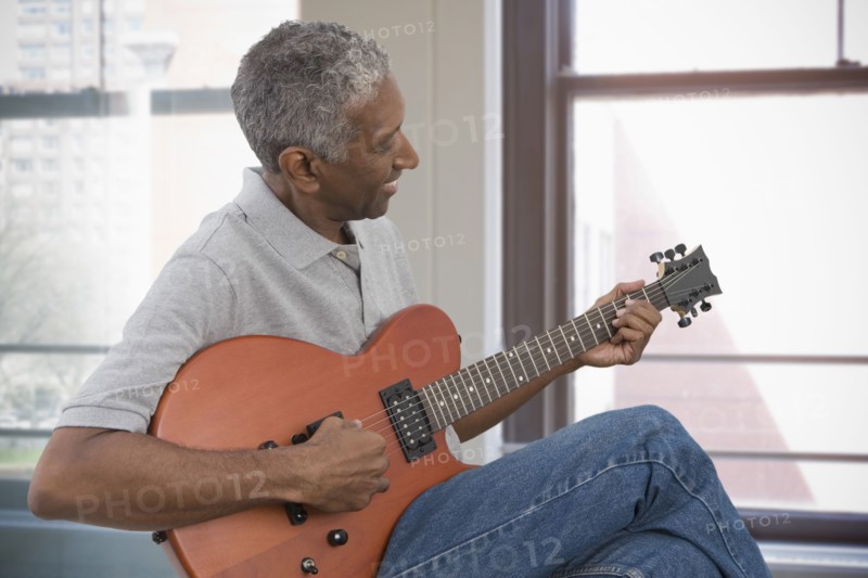 Mixed race man playing electric guitar