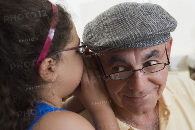 Hispanic girl whispering to grandfather