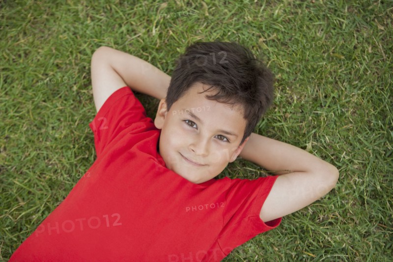 Hispanic boy laying in grass