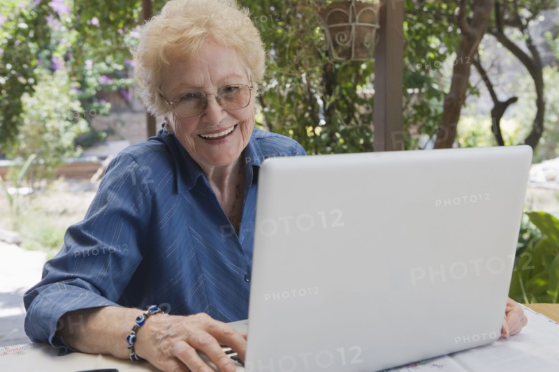 Older Hispanic woman using laptop outdoors