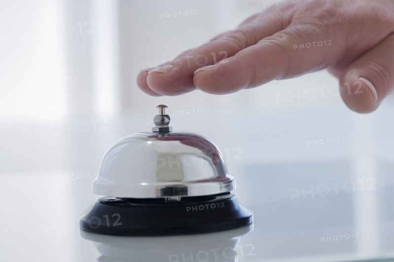 Hispanic man ringing service bell on desk