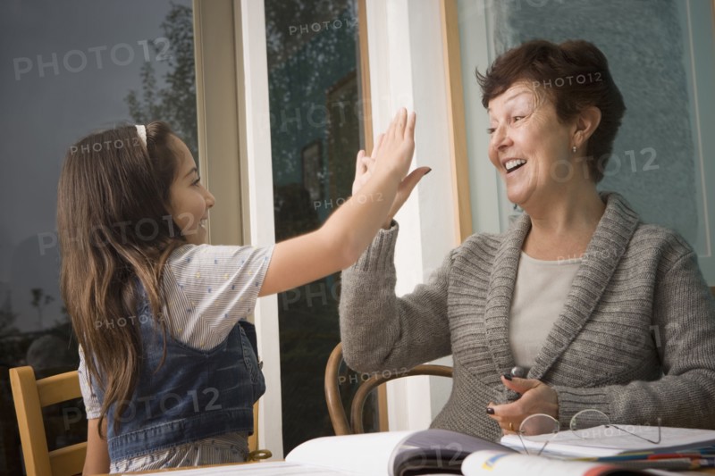 Older Hispanic woman high-fiving granddaughter