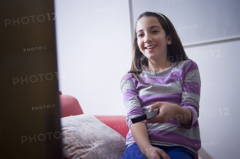 Hispanic girl watching television on sofa