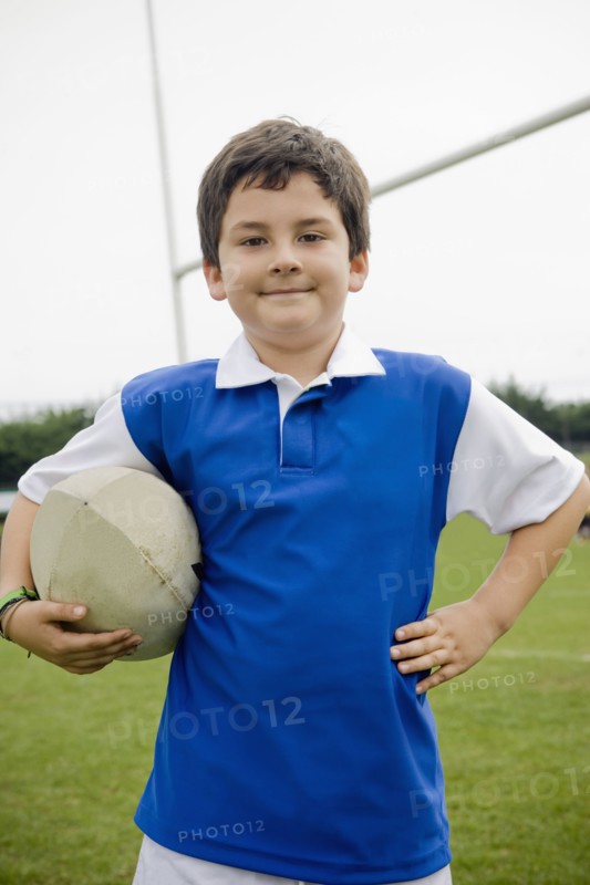 Hispanic boy holding rugby ball on field