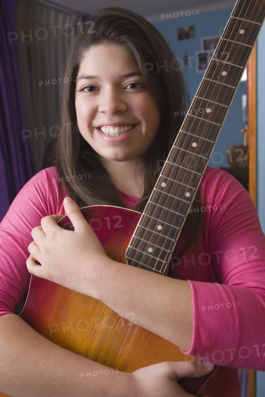 Hispanic girl hugging guitar