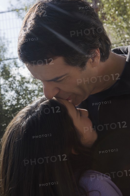 Hispanic man kissing daughter's forehead