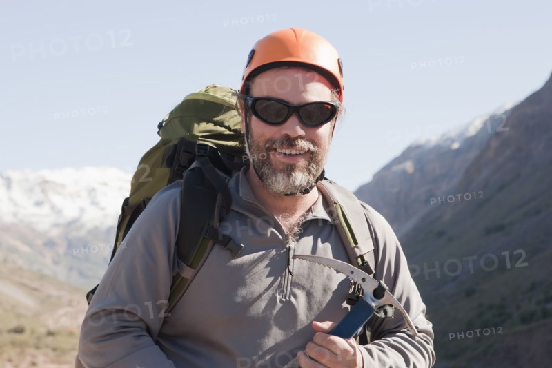Hispanic hiker carrying ice ax in mountains