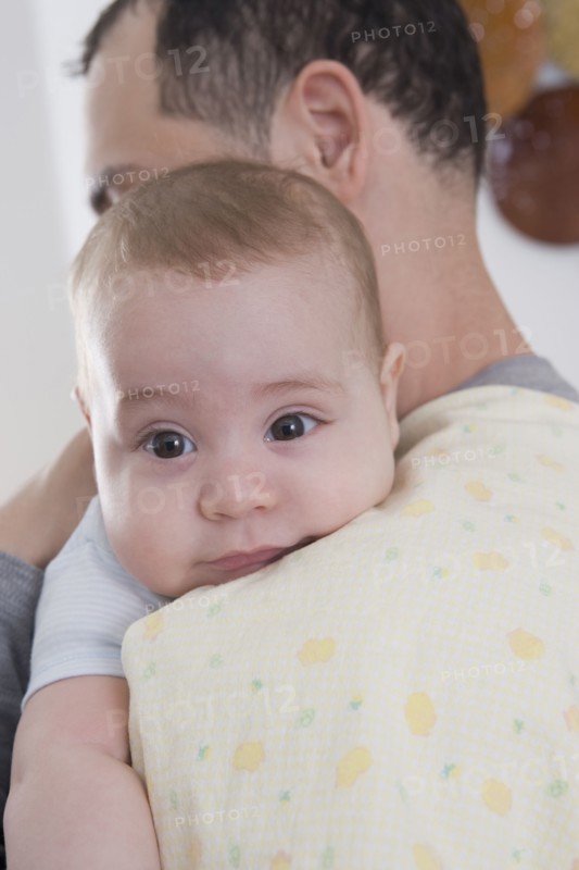 Hispanic father holding baby boy on his shoulder