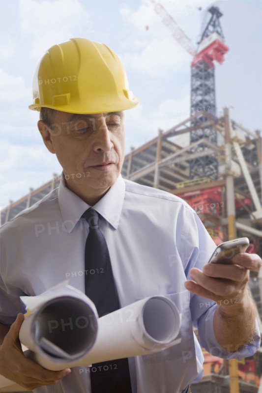 Hispanic architect using cell phone at construction site