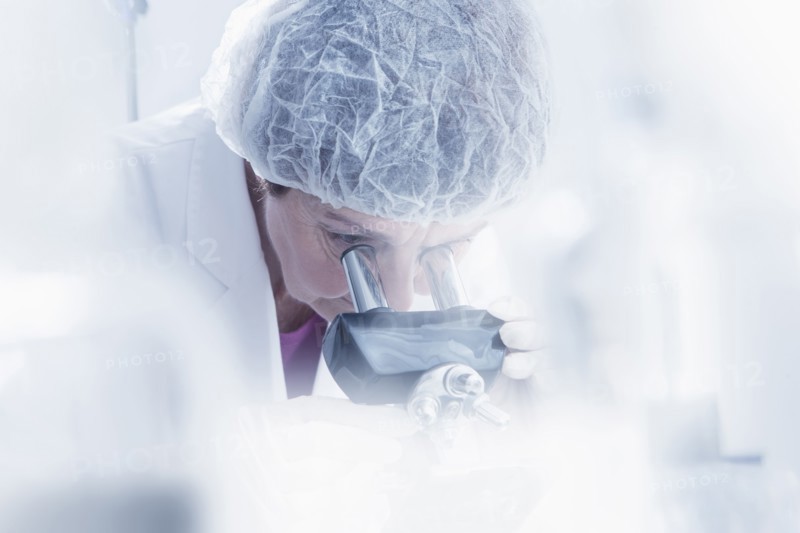 Hispanic scientist using microscope in lab