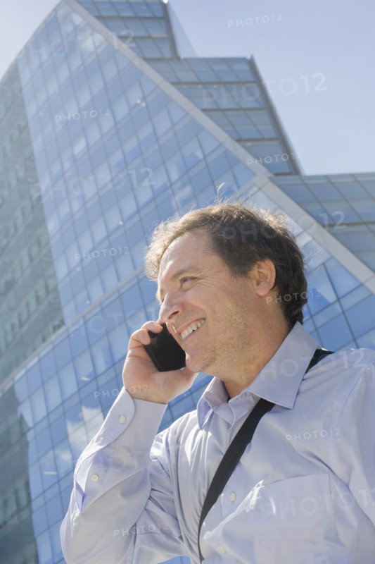 Hispanic businessman talking on cell phone on city street
