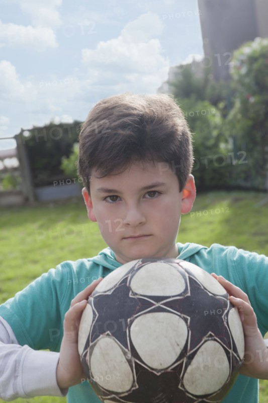 Hispanic boy holding soccer ball in backyard