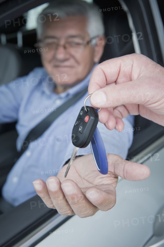 Hispanic car salesman handing keys to customer