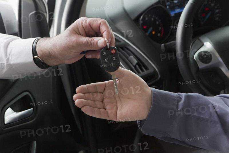 Hispanic car salesman handing keys to customer