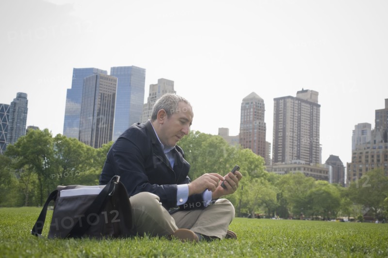 Hispanic businessman using cell phone in urban park