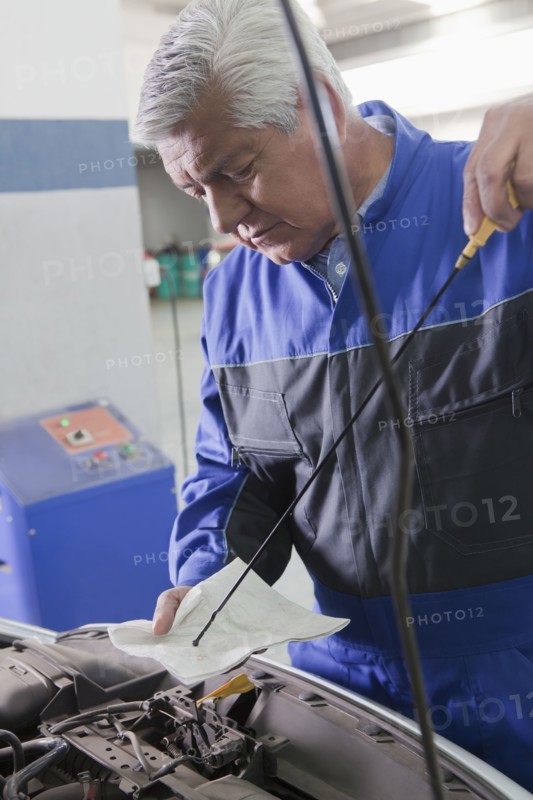 Older Hispanic mechanic repairing car in garage