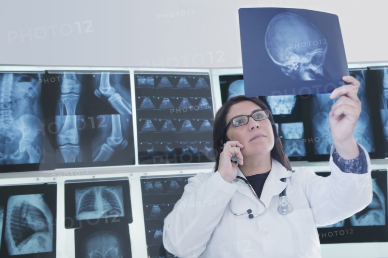 Hispanic doctor examining x-rays in hospital
