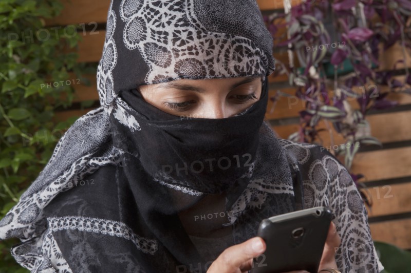 Hispanic woman in headscarf using cell phone