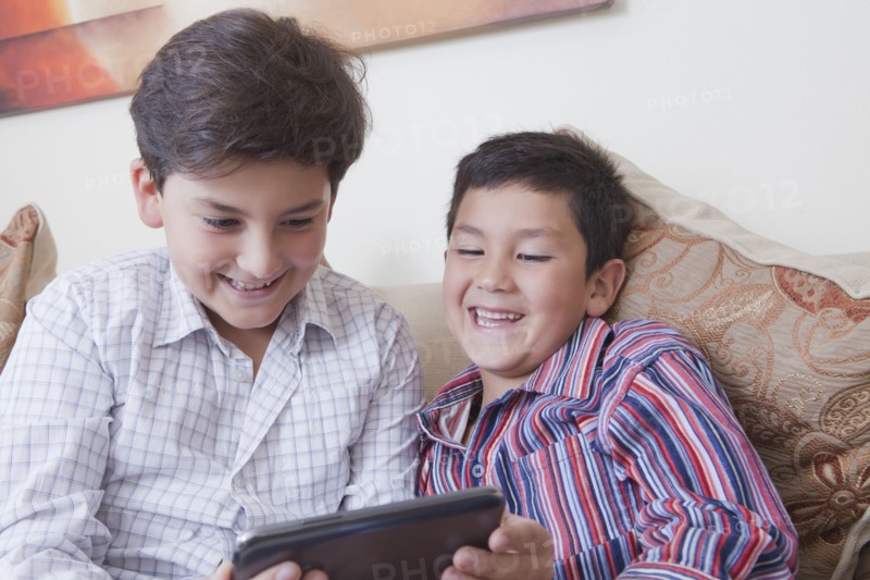 Hispanic brothers using digital tablet
